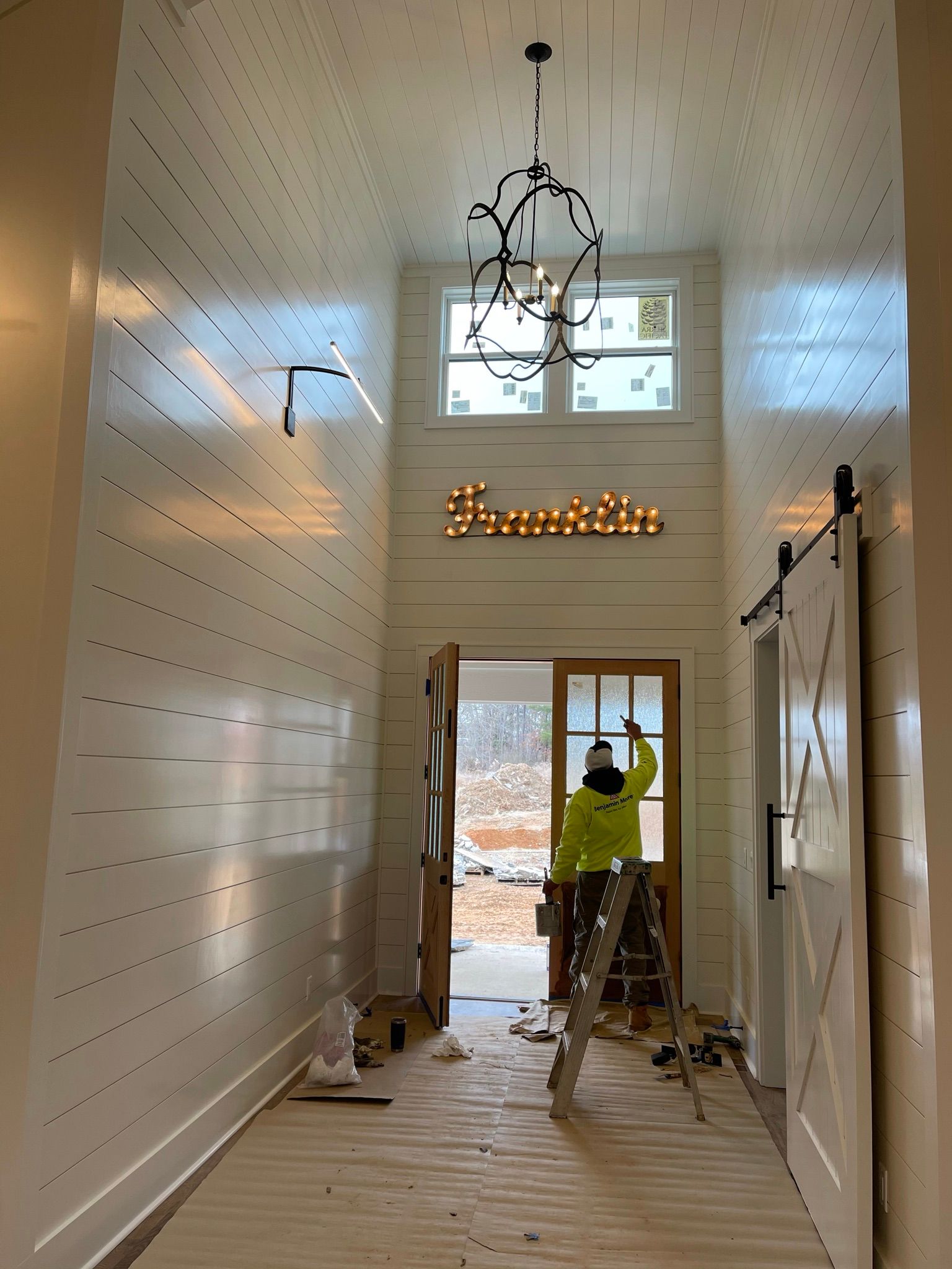 A man is standing in a hallway painting a wall.