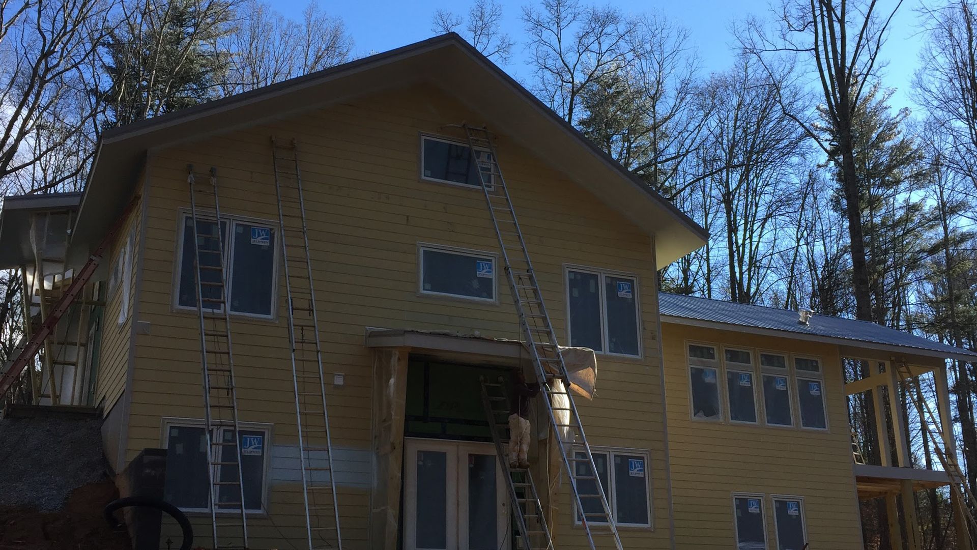 A large yellow house with a ladder in front of it is being built.