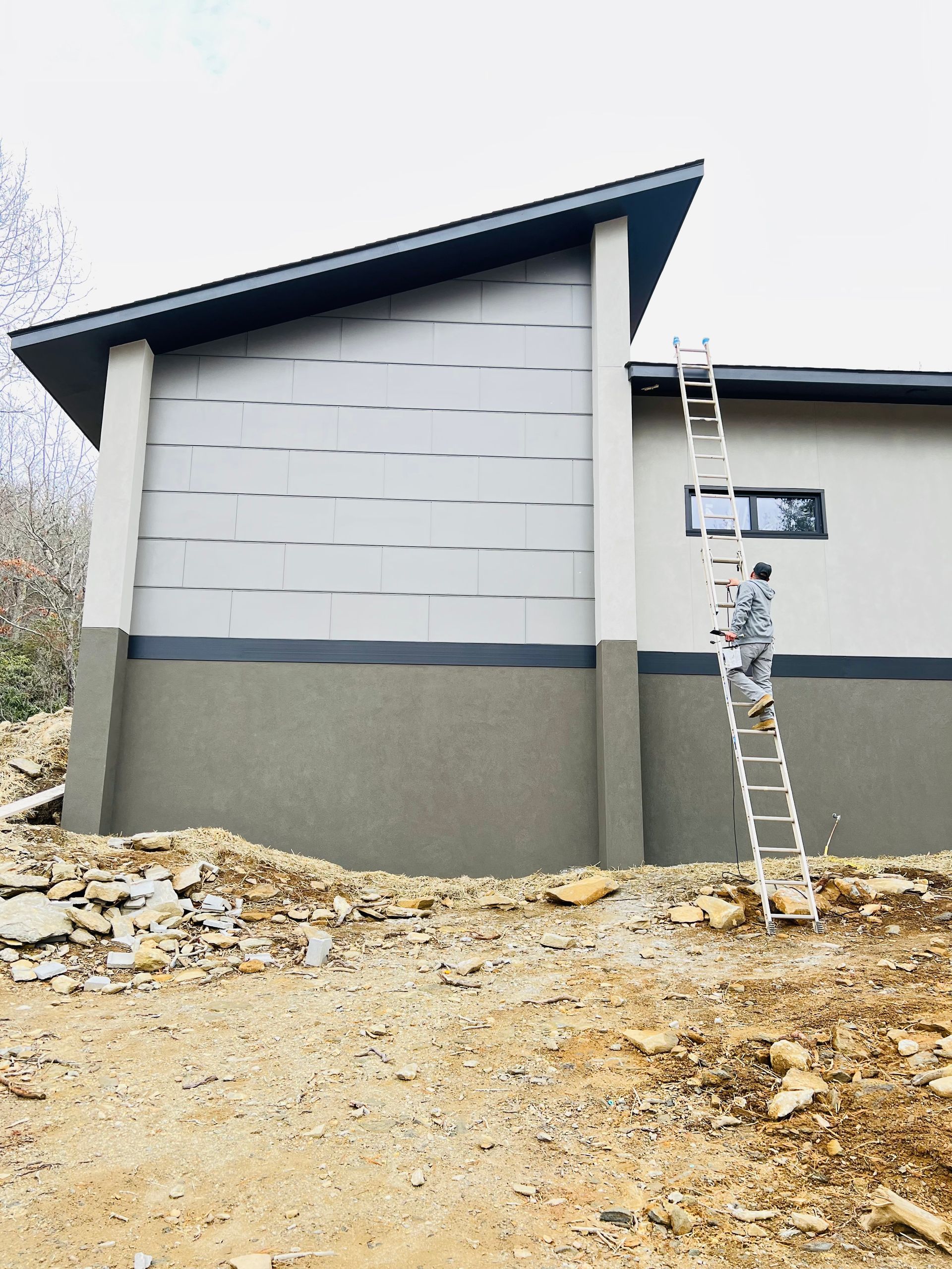 A man is standing on a ladder on the side of a building.