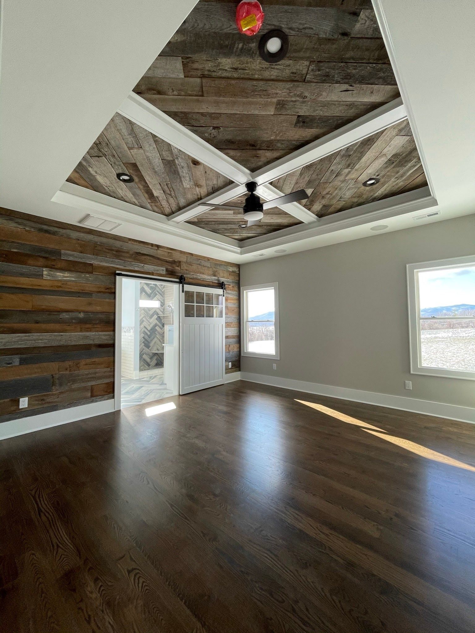 An empty room with a wooden wall and ceiling and a ceiling fan.