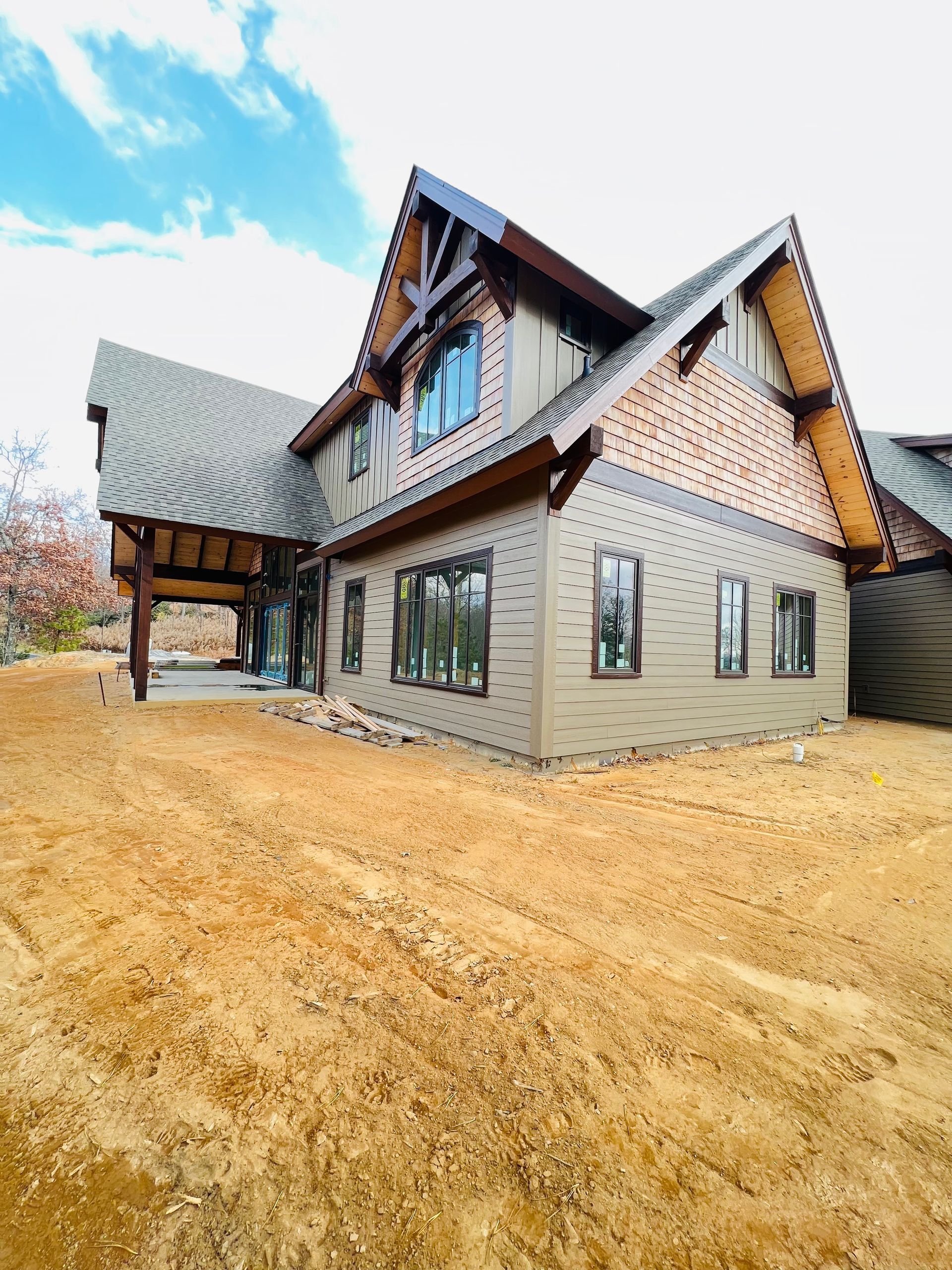 A large house with a lot of windows is sitting on top of a dirt field.