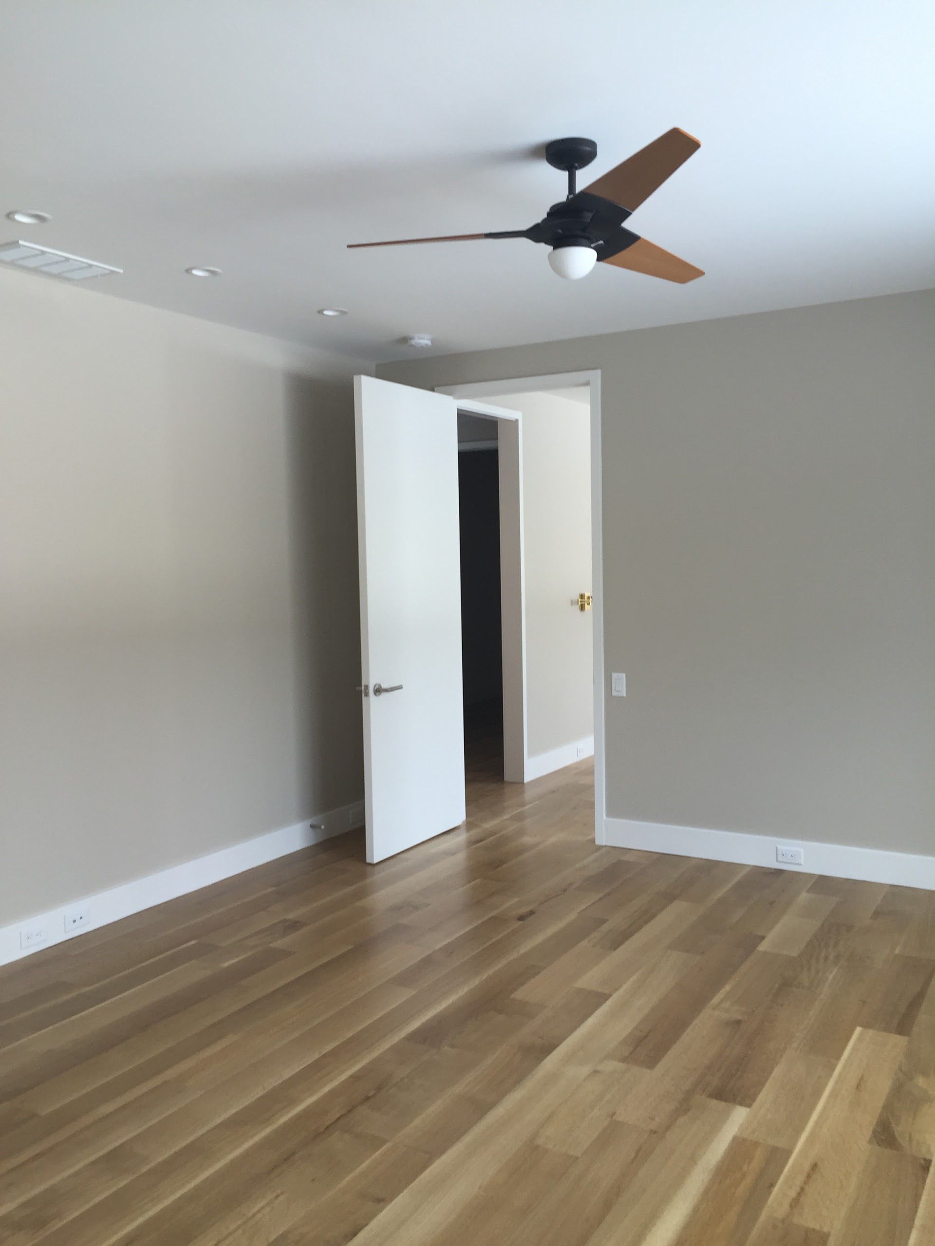 An empty room with hardwood floors and a ceiling fan