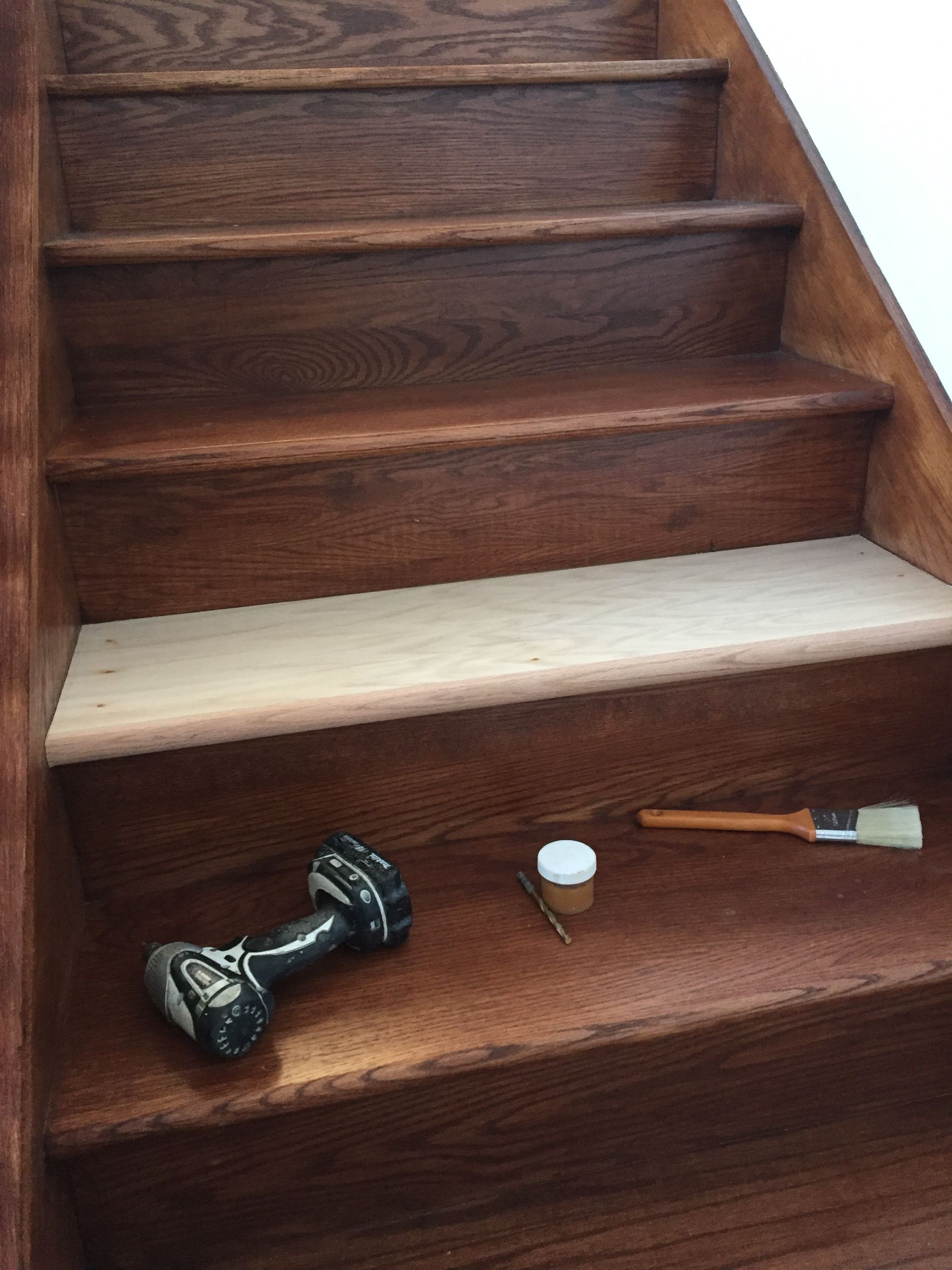 A wooden staircase with a drill and brush on the steps.
