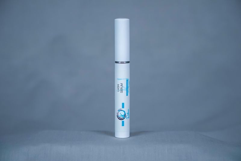 White tube of lash serum on a fluffy, white surface; 