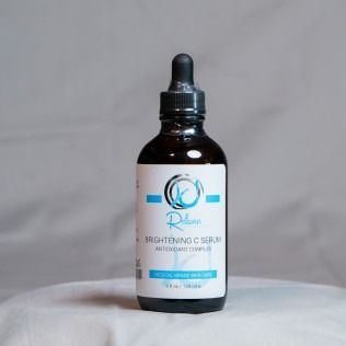A brown bottle of Brightening C Serum with a dropper. The label is white and light blue.