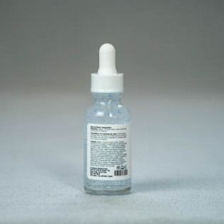 Bottle of skincare serum with a dropper against a gray background.