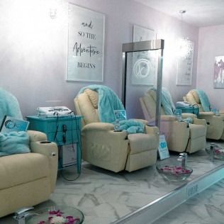 A spa room with recliner chairs, a side table, and wall art.