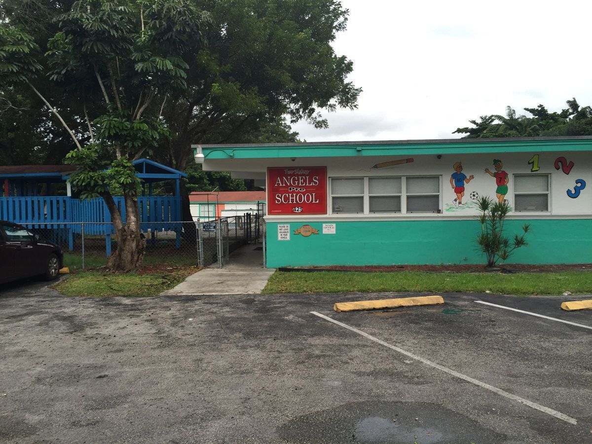 A green and white building with a red sign that says kindergarten school