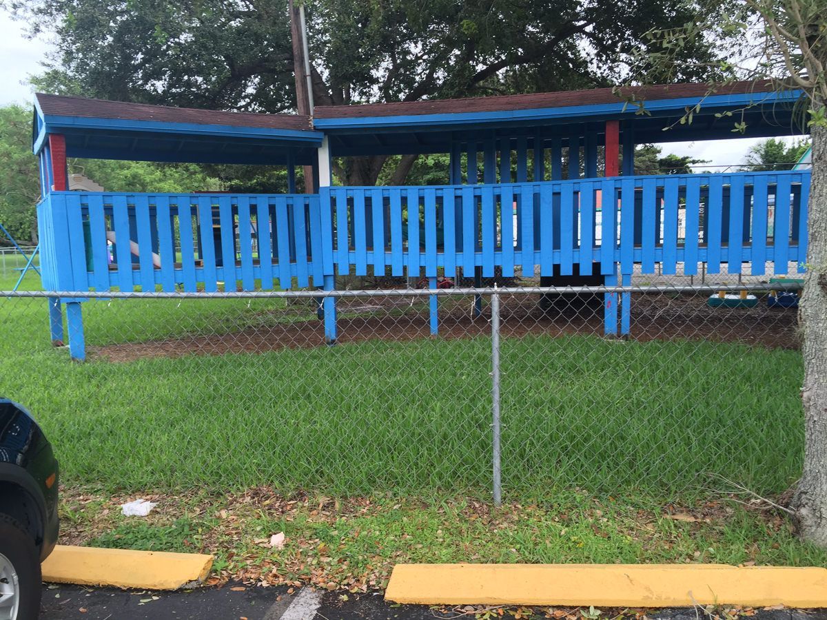 A blue fence is surrounded by a chain link fence in a park.