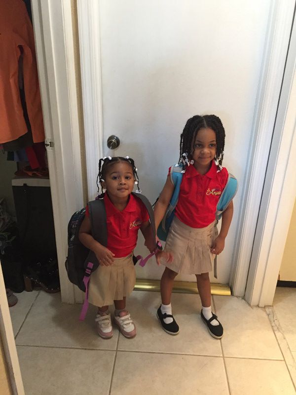 Two little girls are standing next to each other in front of a door.