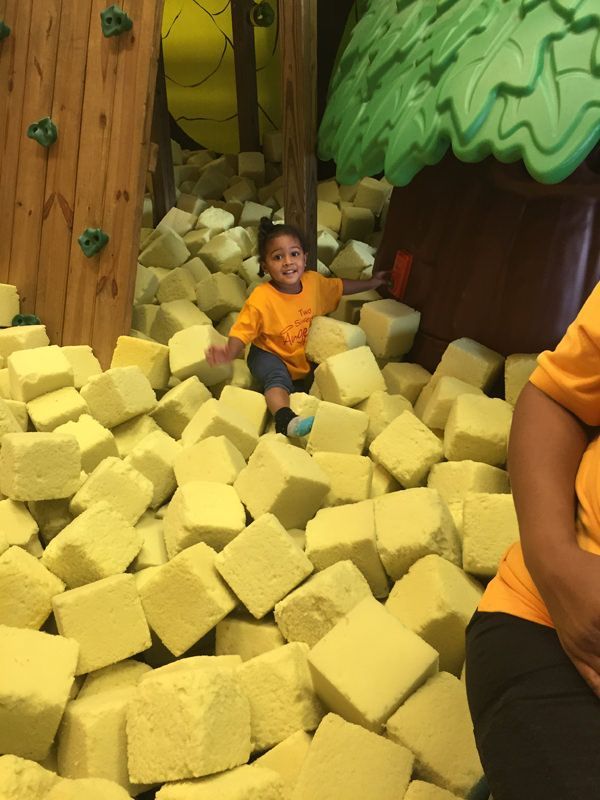 A little boy is sitting in a pile of foam cubes