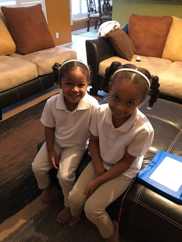 Two little girls are sitting next to each other on a couch