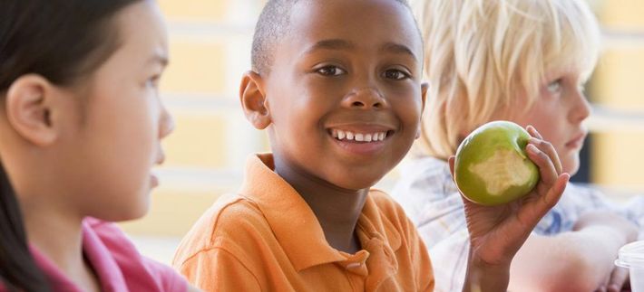 A group of children are sitting in a classroom eating apples.