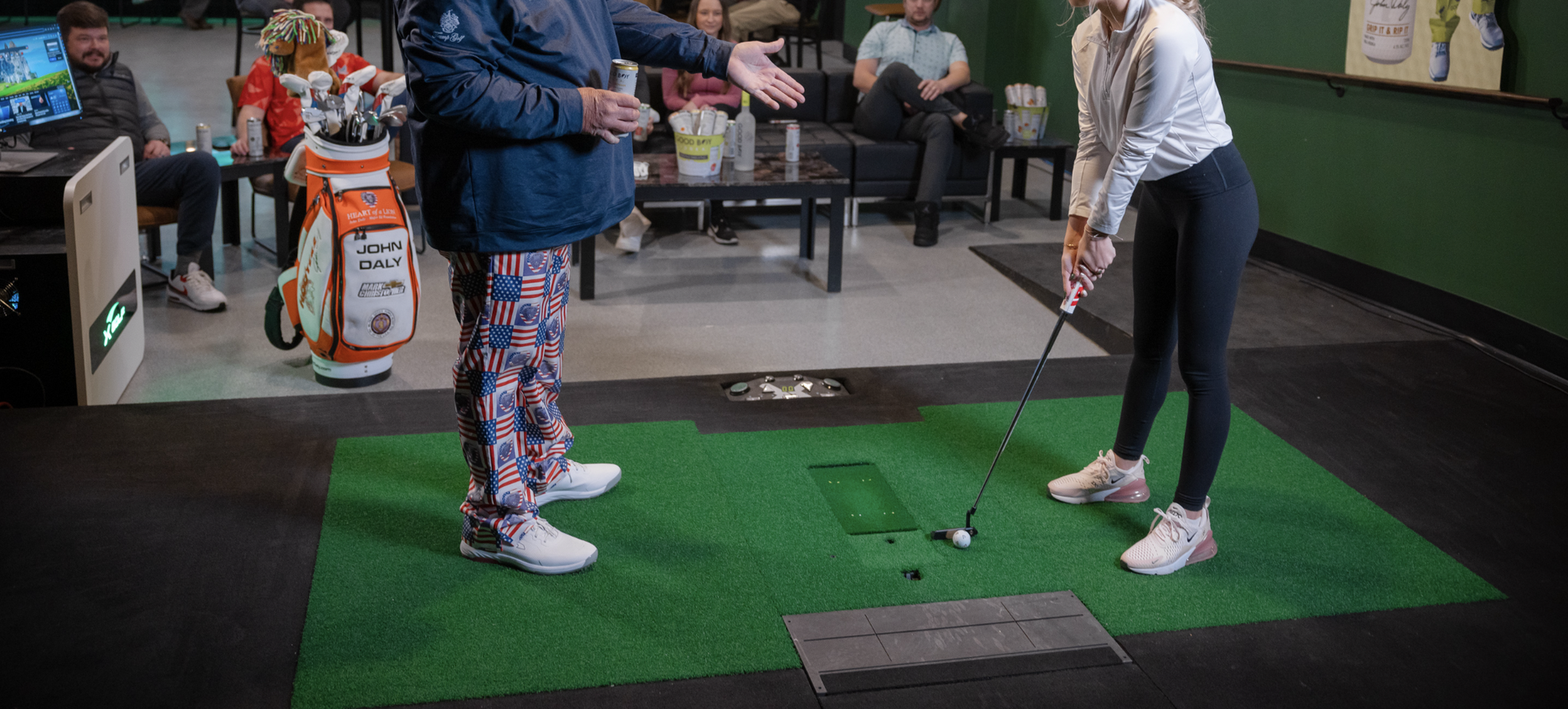 Man coaching woman on a golf course. Man kneels, pointing at ball; woman puts. Another woman watches.