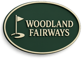 Oval sign for Woodland Fairways golf course, green background, gold border, and text with golf flag icon.