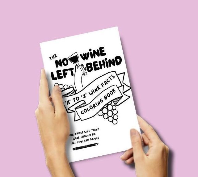 Two hands holding No Wine Left Behind’s interactive wine coloring book with a white cover and black design, titled “A to Z Wine Facts Coloring Book.”