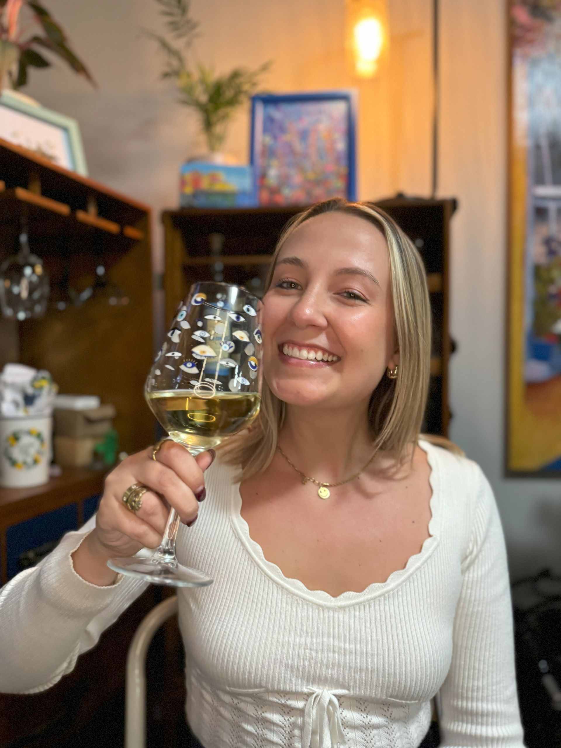 Creative partner of No Wine Left Behind, smiling with a glass of white wine