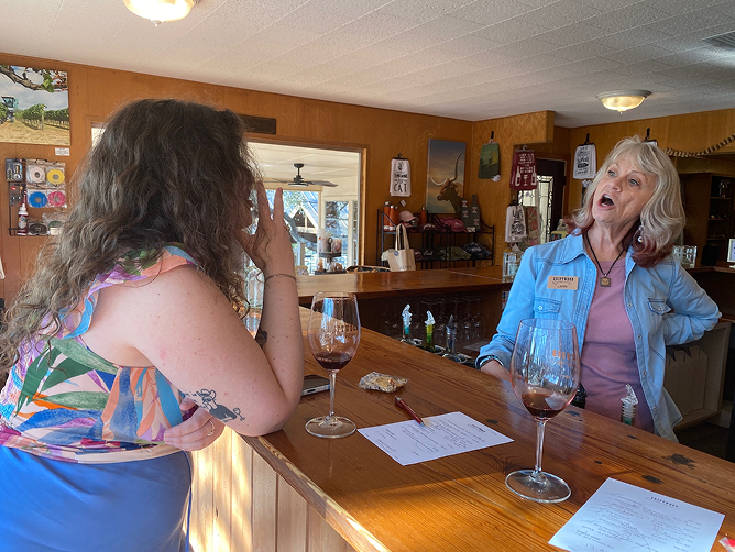 Two women deep in discussion with glasses of wine in front of them, illustrating collaboration in curating wine experiences