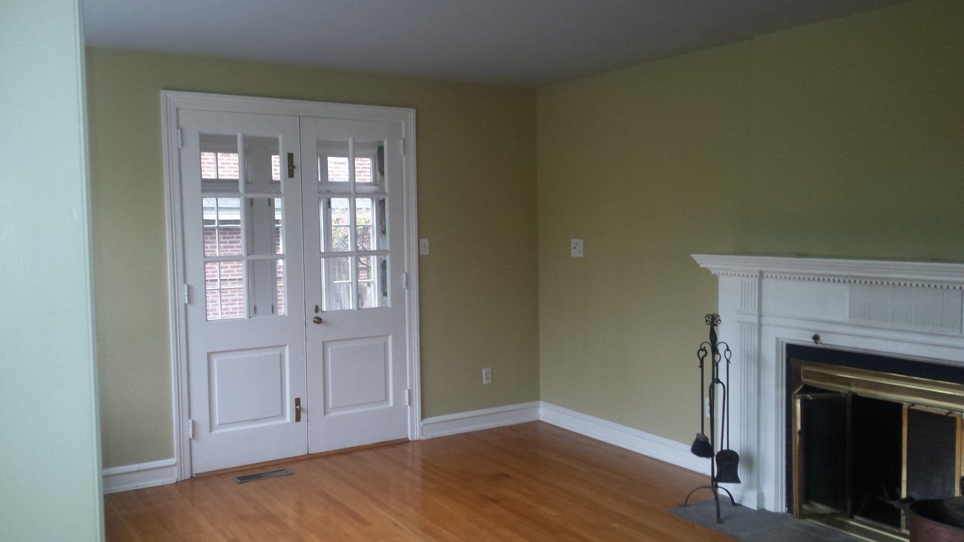 An empty living room with a fireplace and sliding glass doors.