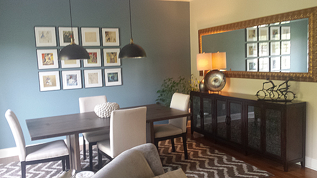 A dining room with a table and chairs and a large mirror.