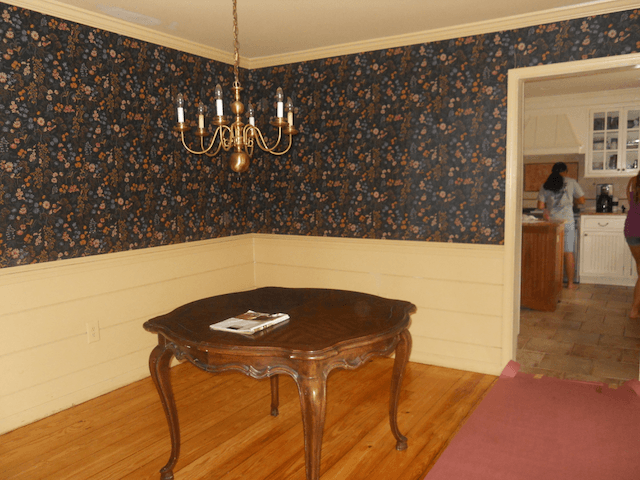 A dining room with a table and a chandelier hanging from the ceiling