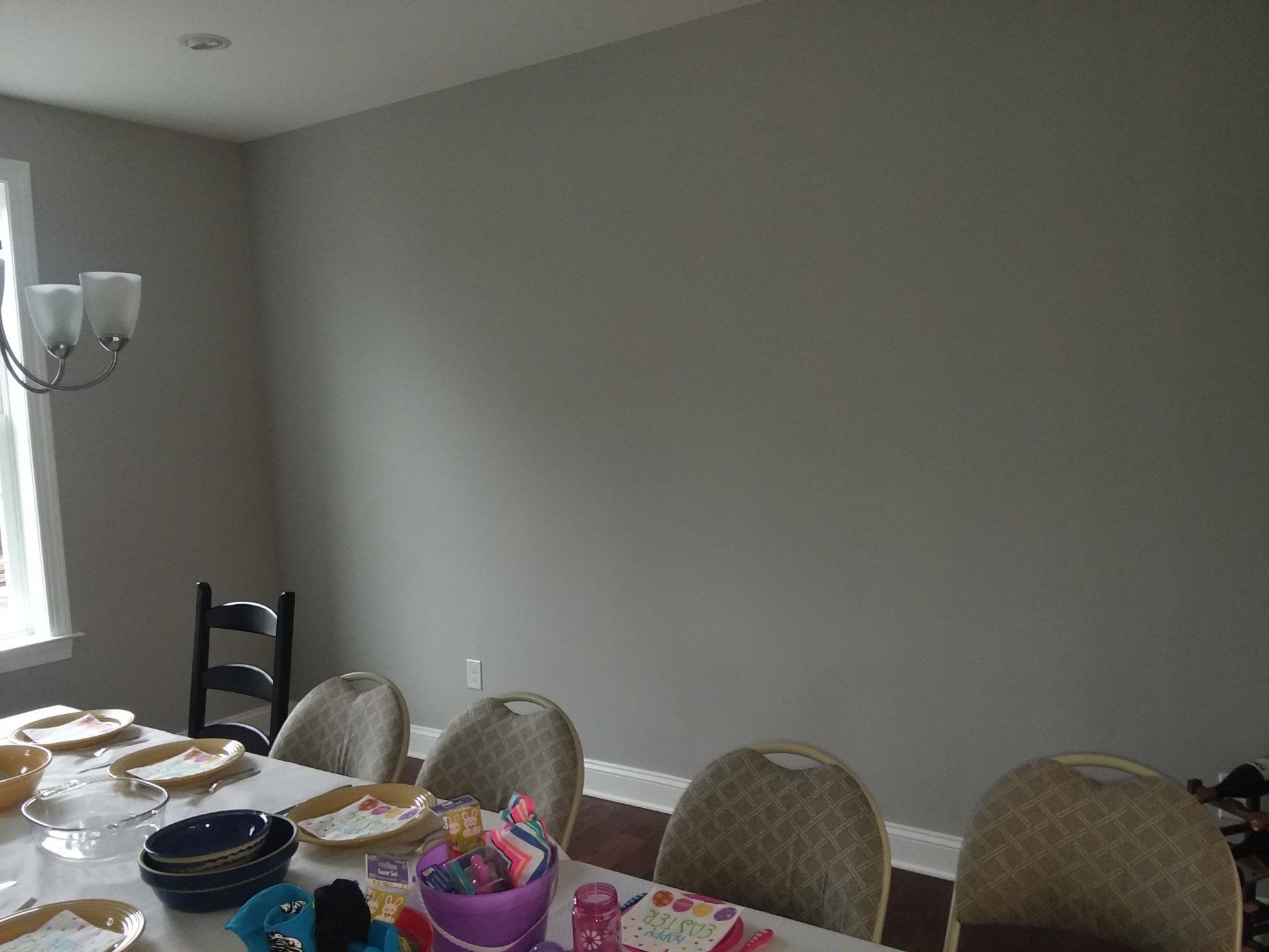 A dining room table with plates , bowls , and a chandelier.