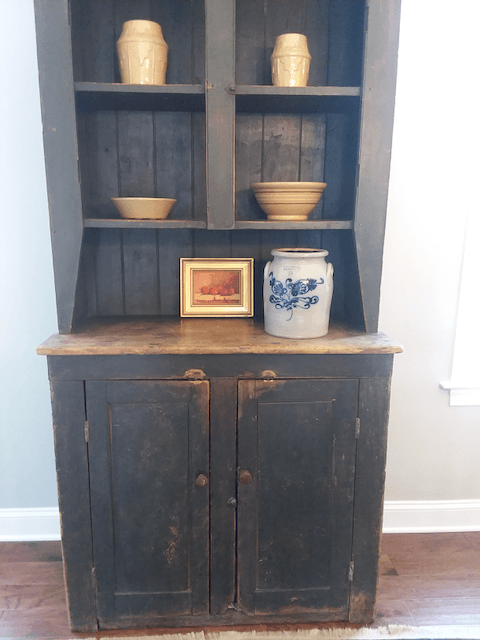 A black cabinet with a blue and white vase on top of it