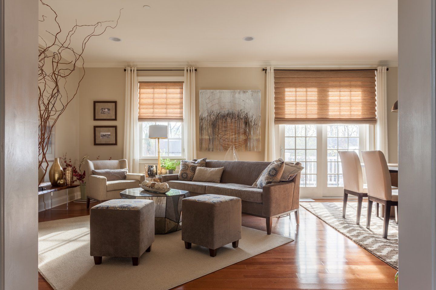 A living room with a couch and ottomans and a dining room in the background