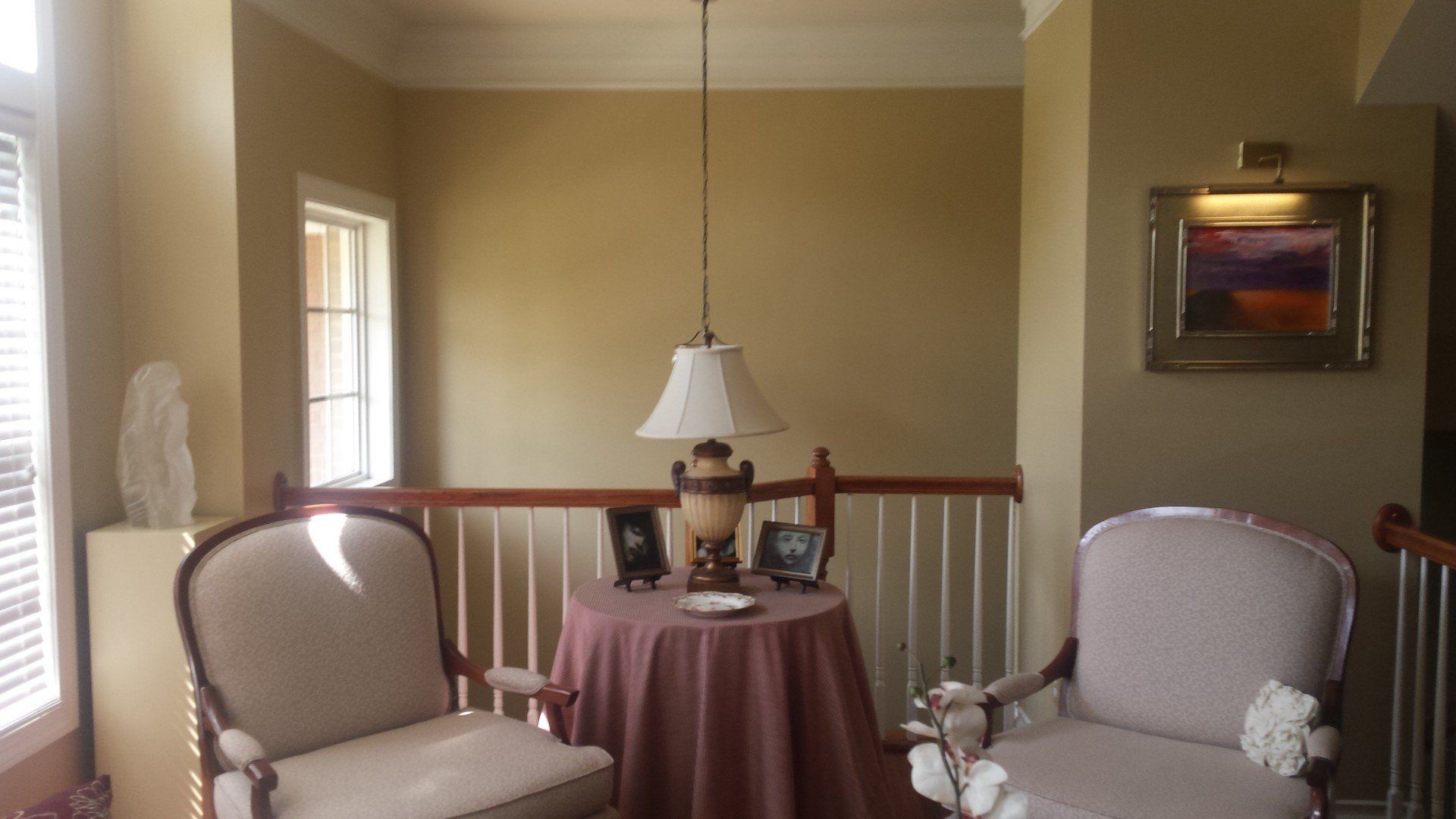 A living room with two chairs and a table with a lamp on it
