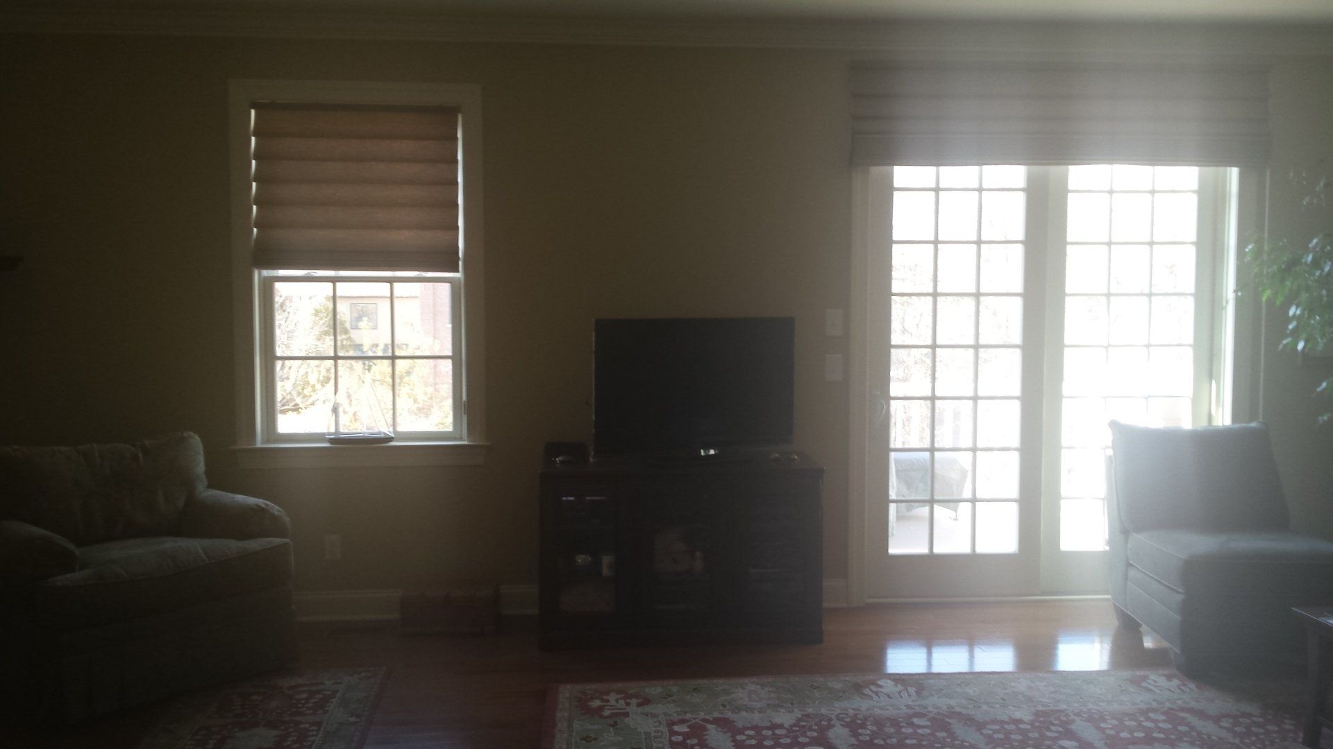 A living room with a couch , television , and sliding glass doors.