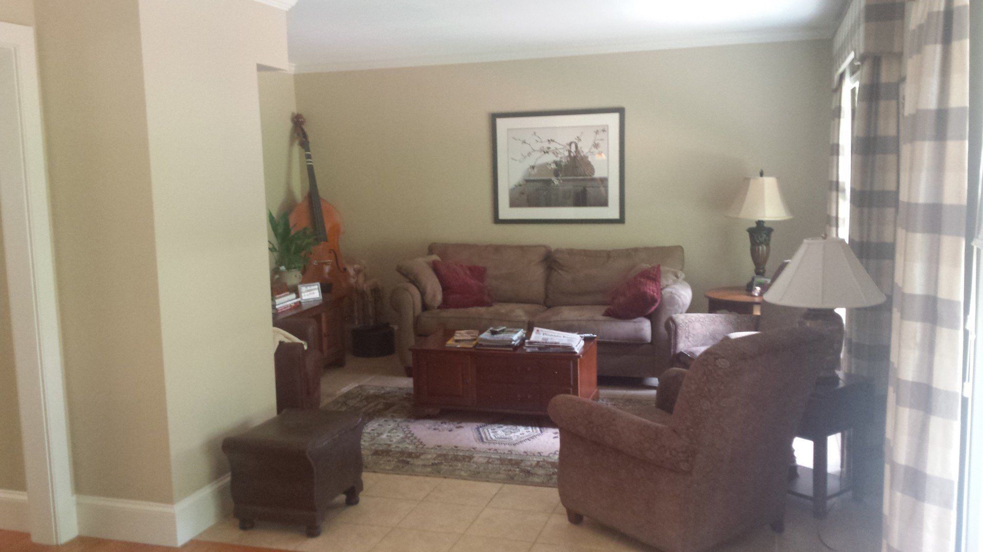 A living room with a couch , chairs , lamps and a picture on the wall.