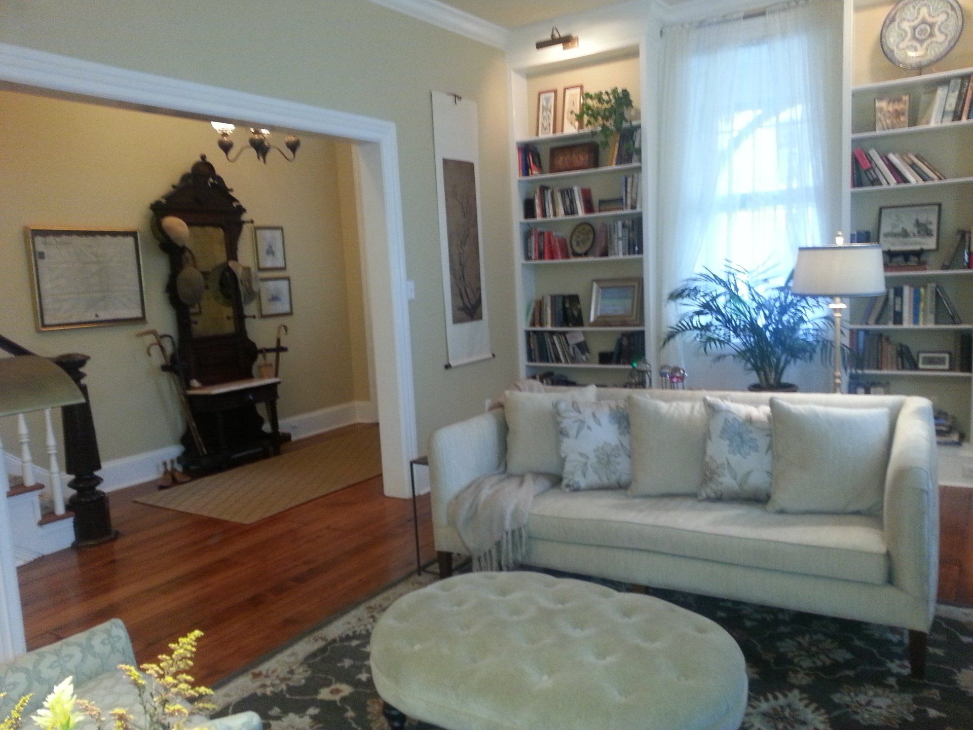 A living room with a white couch and a round ottoman