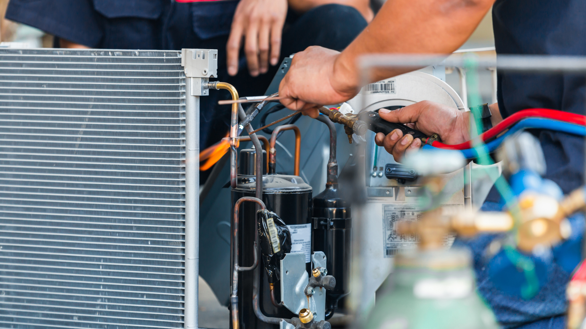 A man is working on a refrigerator with a welding torch.