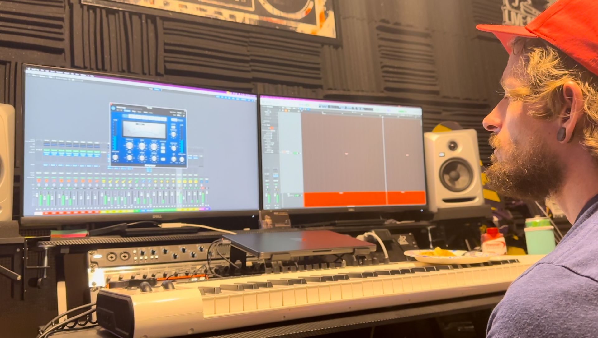 A man is sitting in front of a keyboard in a recording studio.