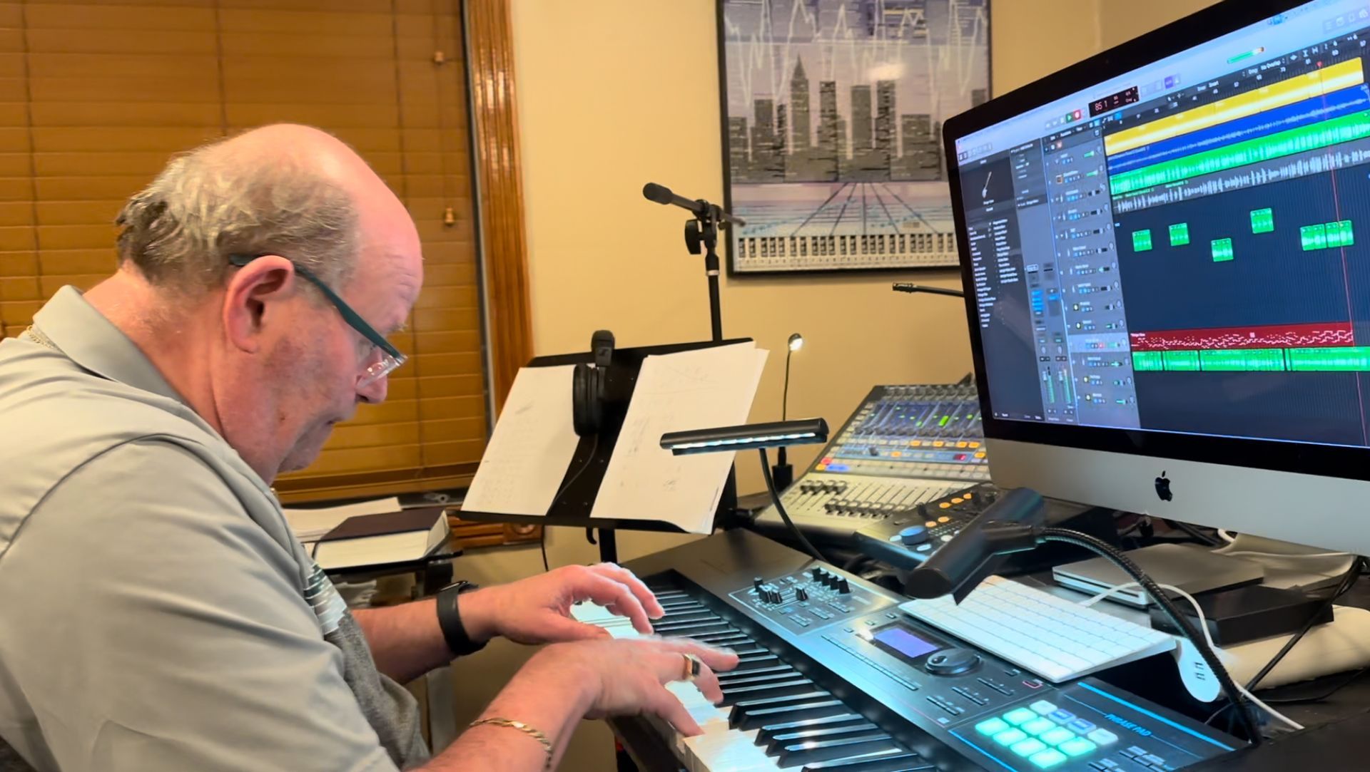 A man is playing a keyboard in front of a computer.