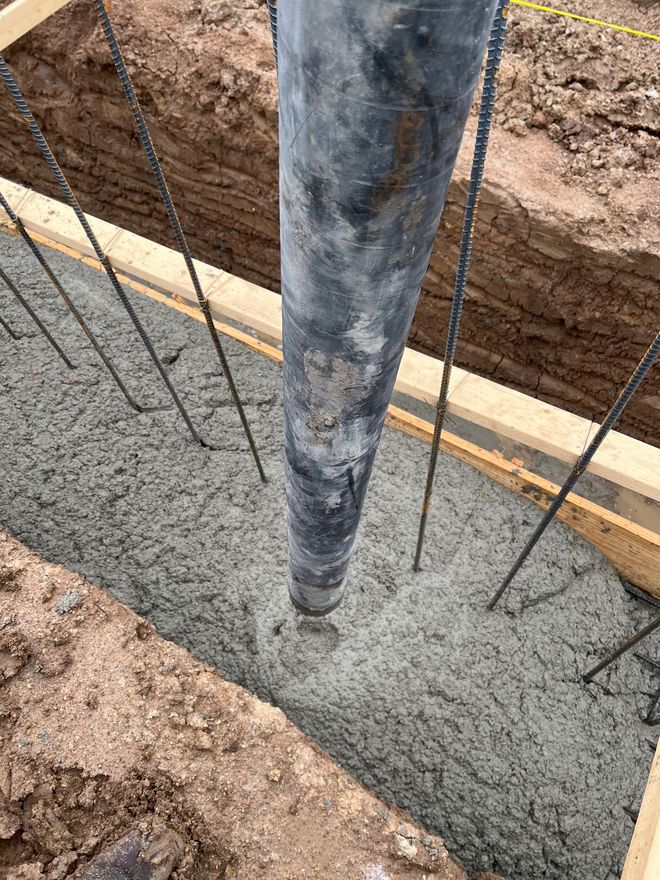 A concrete pump is pumping concrete into a hole in the ground.