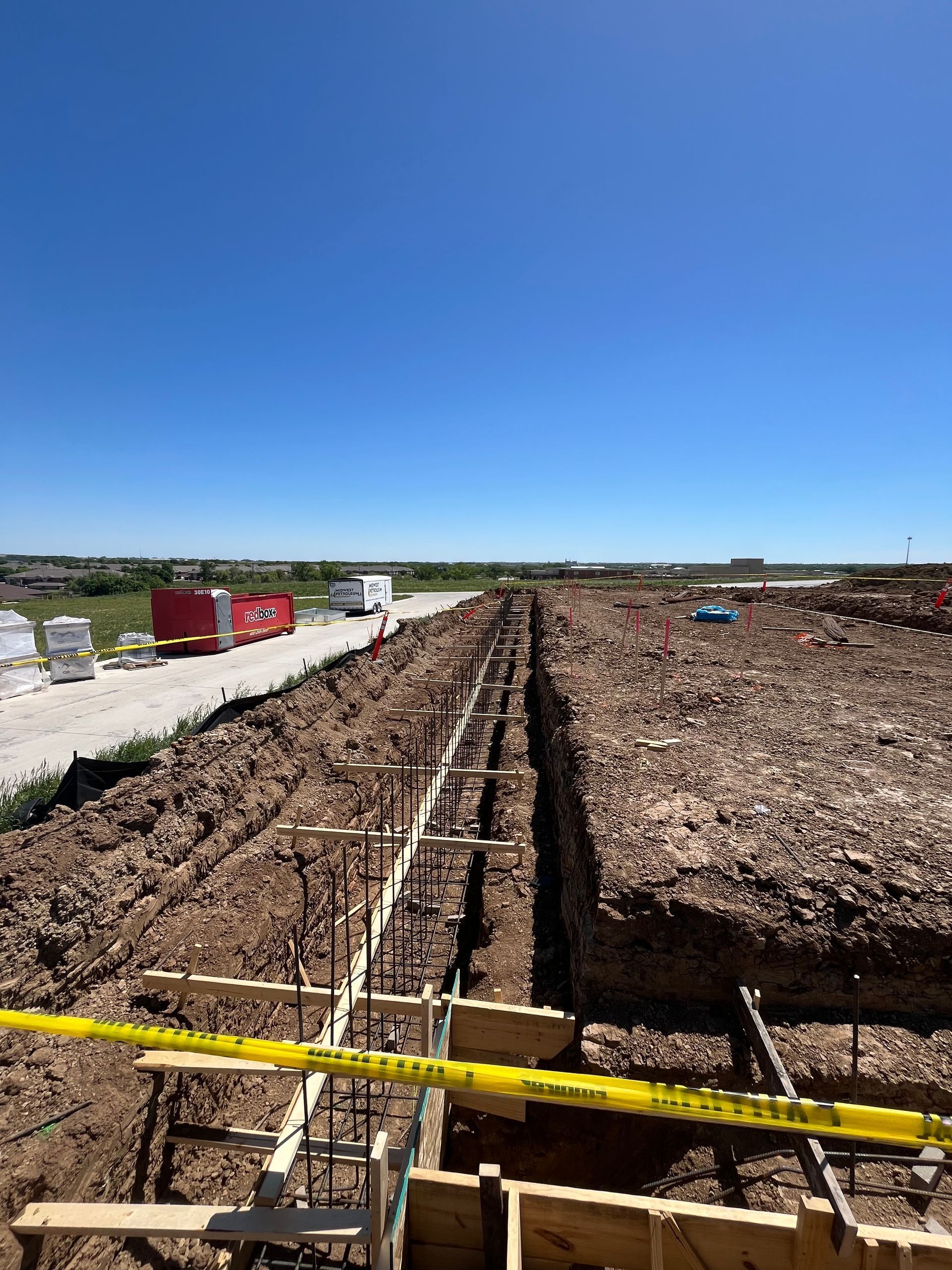 A construction site with a lot of dirt and a road in the background.