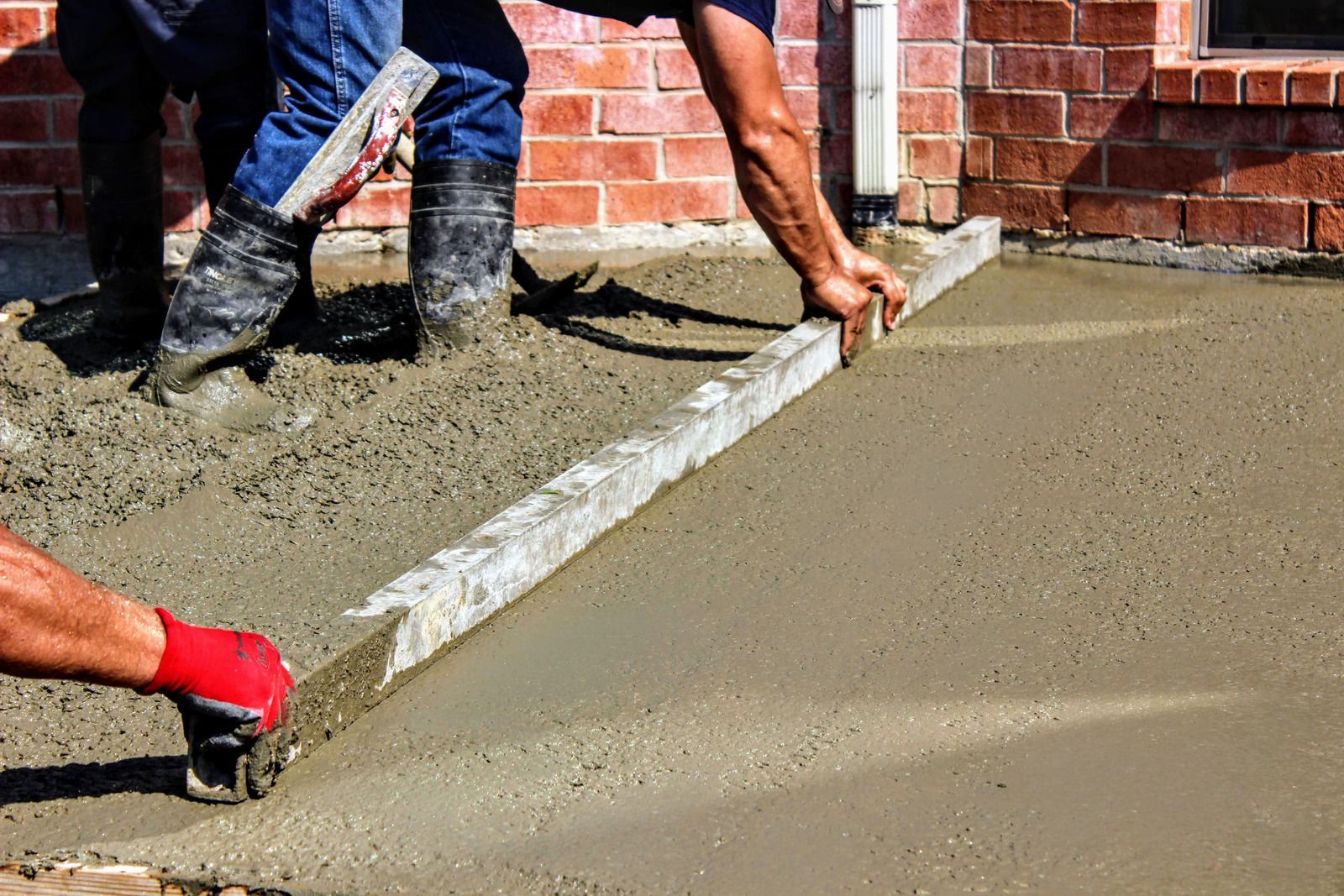 A couple of men are working on a concrete driveway.