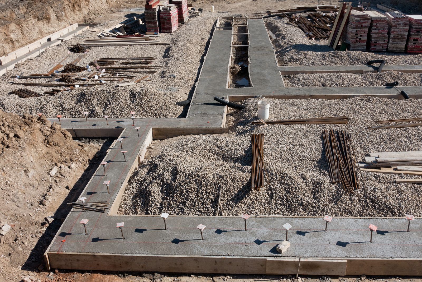 A sidewalk is being built with bricks and tools on the ground.