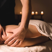 Person receiving a shoulder massage, smiling with eyes closed on a spa table.