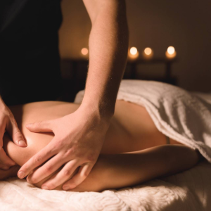 Person receiving a shoulder massage, smiling with eyes closed on a spa table.
