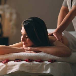 Person receiving a shoulder massage, smiling with eyes closed on a spa table.