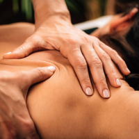 Hands giving a back massage on a person lying face down.