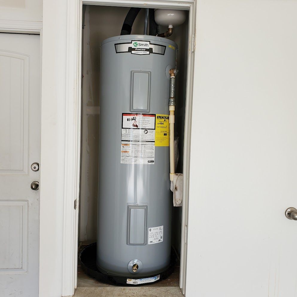A large gray water heater is sitting in a closet next to a door.