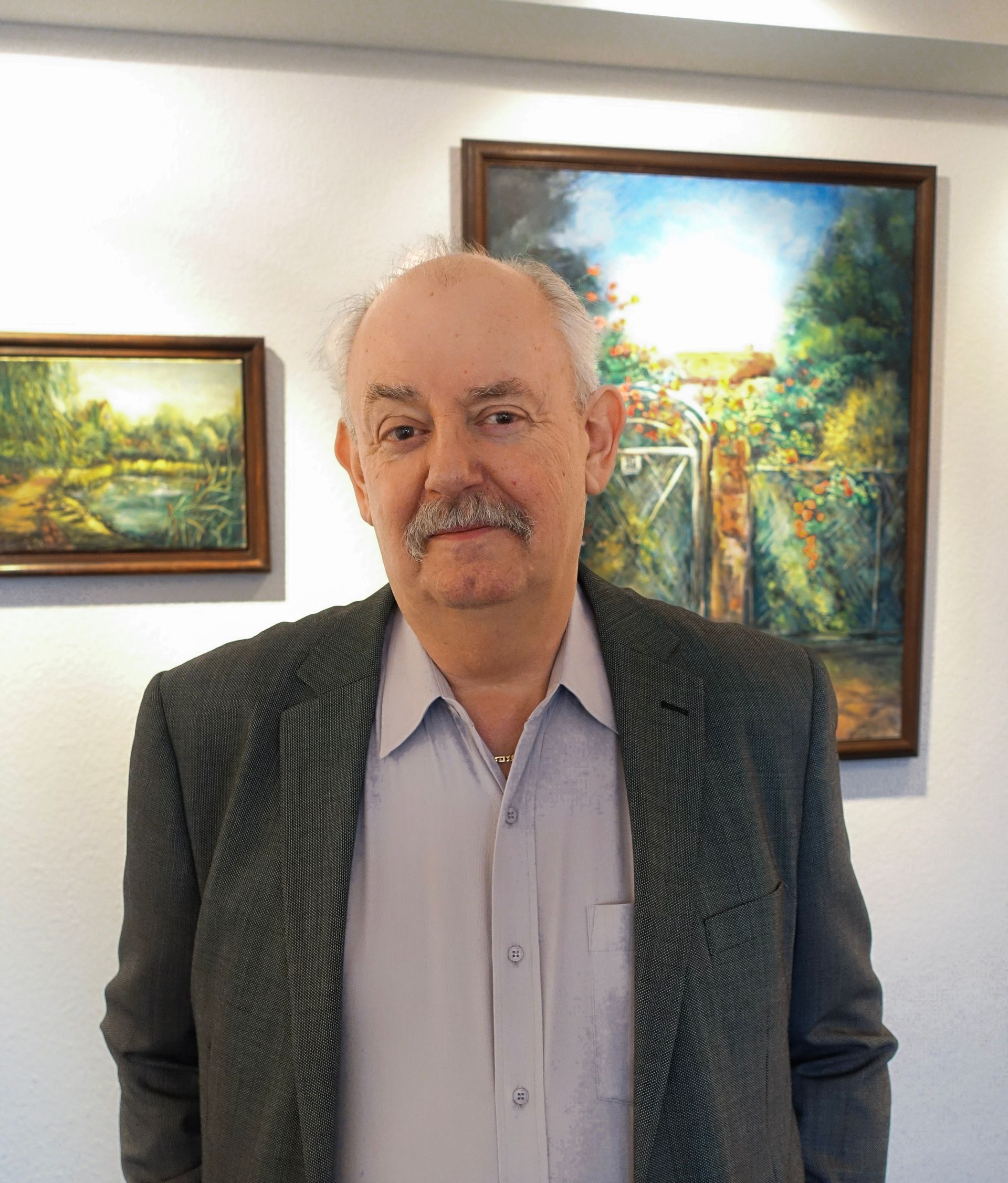 Ein Bild von dem Notar und Rechtsanwalt Klaus Feuersänger, wie er vor Bildern in seiner Kanzlei steht