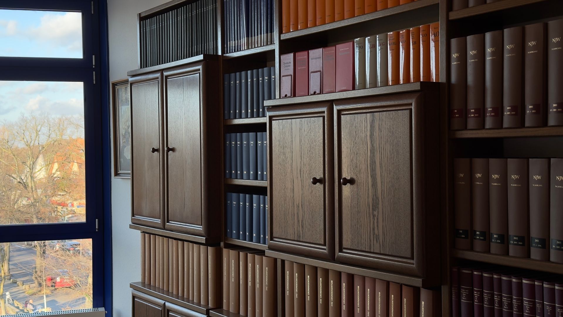 Ein Raum mit vielen Büchern in Regalen und einem Fenster, in der Kanzlei Feuersänger