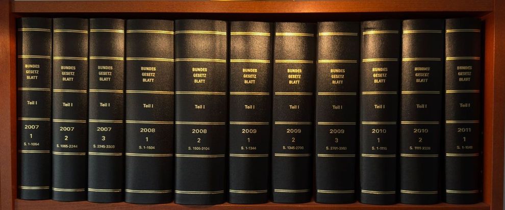 Eine Reihe schwarzer Bücher mit goldenen Einbänden auf einem Regal, in der Kanzlei Feuersänger