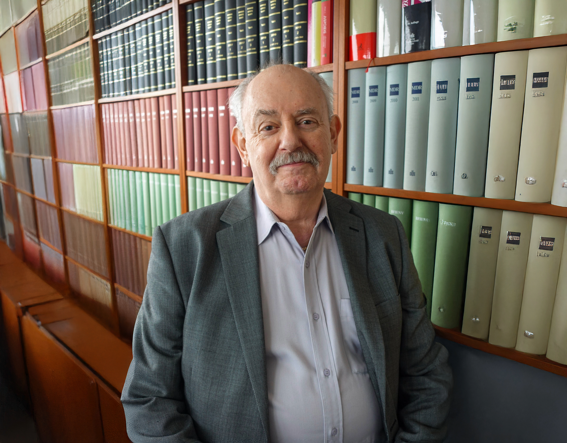 Ein Bild von dem Notar und Rechtsanwalt Klaus Feuersänger, wie er vor einem Bücherregal sitzt