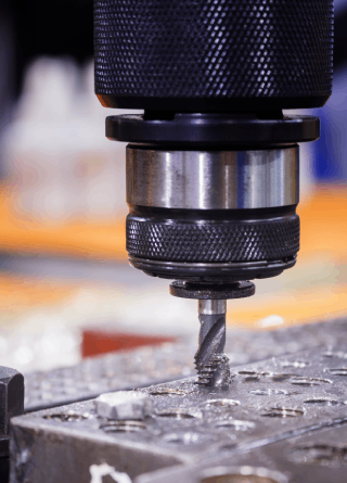 A drill is cutting a hole in a piece of metal.