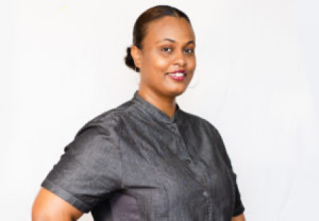 A woman in a black shirt is standing in front of a white background.